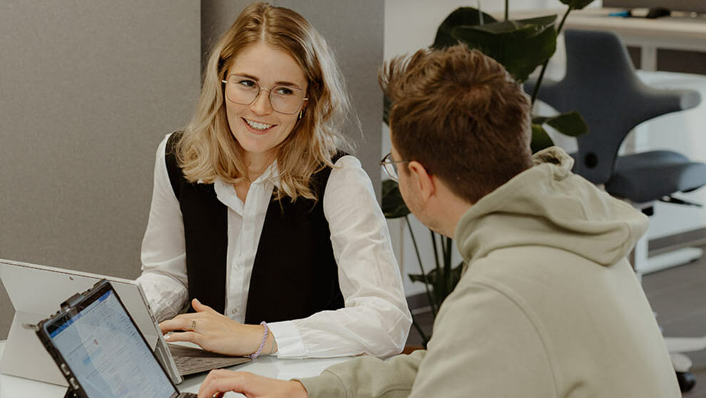 Frau und Mann sitzen am Tisch und arbeiten am PC